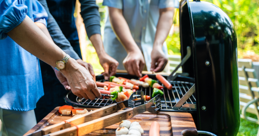 people placing food items on a grill